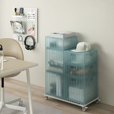 a desk with a chair and some plastic containers on top of it next to a white wall