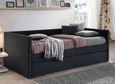 a black daybed with pillows and blankets on it