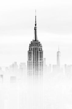 a black and white photo of the empire building in new york city, with fog