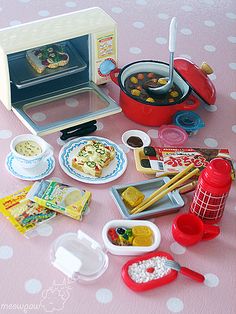 there are many toys on the table with food in front of it, including a toaster oven