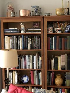 a bookshelf filled with lots of books next to a lamp