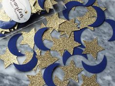 blue and gold glitter stars cut out on a marble table with a bottle of wine