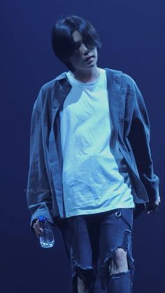 a young man in ripped jeans and a white t - shirt is holding a water bottle