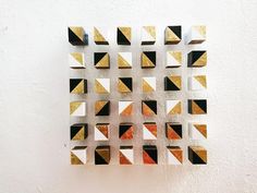 a white wall with some gold and black squares on it's side, against a white wall