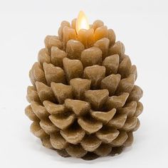 a candle that is sitting on top of a pinecone shaped like a cone