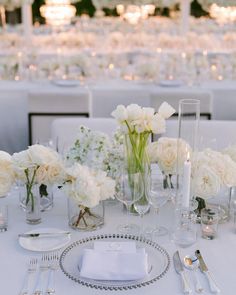 the table is set with white flowers and silverware