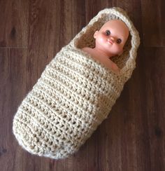 a doll in a crocheted bag laying on the floor with it's head sticking out