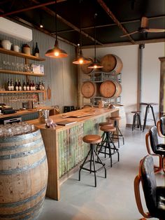 a bar with several wooden barrels and stools