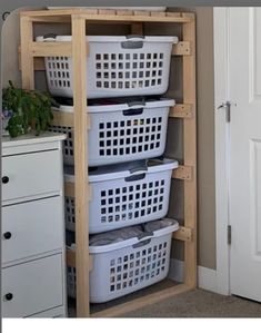 three white baskets are stacked on top of each other in the corner of a room