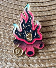 a pink and blue fireball pin sitting on top of a straw hat covered in woven material