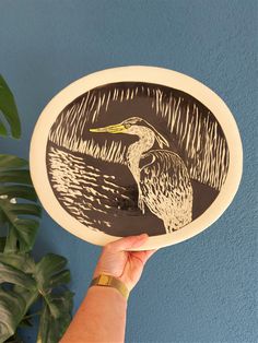 a hand holding a paper plate with a drawing of a bird on it's side