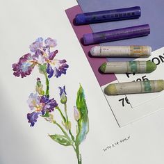 three crayons are next to some flowers on a sheet of paper with markers