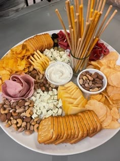 a white plate topped with lots of different types of snacks and crackers on top of it