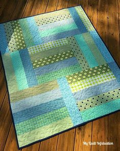 a blue and green quilt on a wooden floor