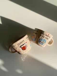 two coffee mugs sitting next to each other on top of a white countertop