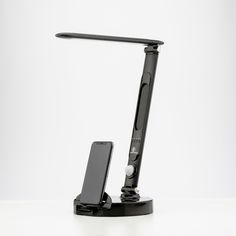 a desk lamp with a cell phone attached to the arm and one light on it