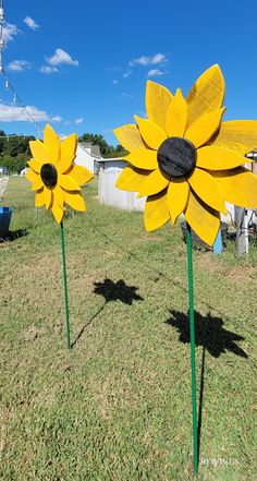 two fake sunflowers sitting in the grass next to each other on a sunny day