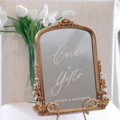 a mirror sitting on top of a table next to a vase filled with white flowers