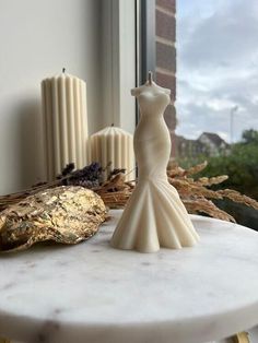 a white cake with a dress on it next to some candles and other decorations in front of a window