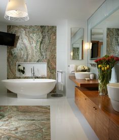 a bathroom with marble walls and flooring, two sinks and a large bathtub