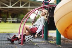 a woman sitting on top of a swing next to a basketball ball and playground equipment