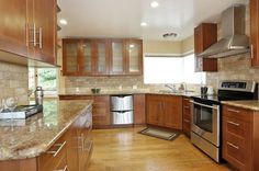 a large kitchen with wooden cabinets and stainless steel appliances, including an oven, dishwasher, sink, microwave, and refrigerator