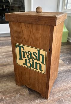 a wooden trash bin sitting on top of a hard wood floor