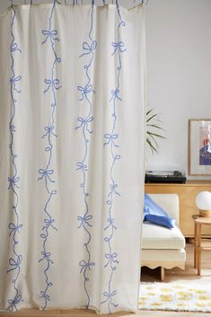 a white curtain with blue bows hanging from it's side in a living room