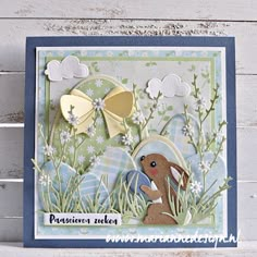 a card with an image of a bunny and eggs in the grass, on a wooden background