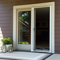 an open sliding glass door on the side of a house next to a planter