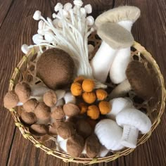 a basket filled with lots of different types of mushrooms on top of a wooden table