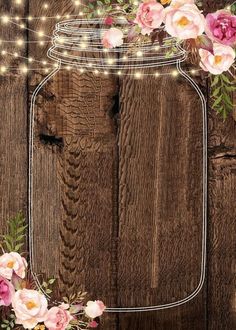 a mason jar filled with pink flowers on top of a wooden table next to string lights