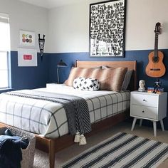 a bed room with a neatly made bed and a guitar on the wall