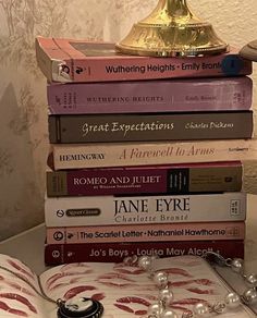 a stack of books sitting on top of a table next to a golden trophy and lamp