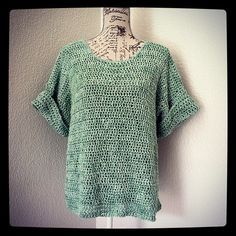 a green crocheted top hanging on a white wall