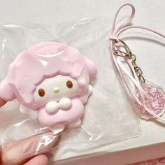 a pink hello kitty keychain sitting on top of a white table next to a bag