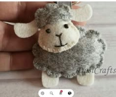 a hand holding a small stuffed animal in the shape of a sheep's head