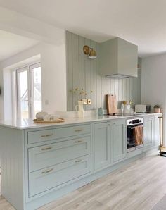 a kitchen with light blue cabinets and white counter tops, gold pulls on the cupboards