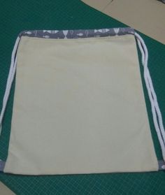 a drawstring bag sitting on top of a cutting mat with scissors and tape