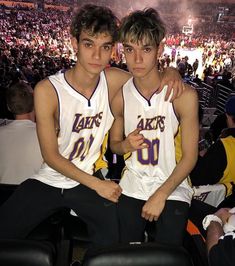 two young men sitting next to each other at a basketball game