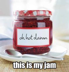 a jar filled with jam sitting on top of a white plate next to a spoon