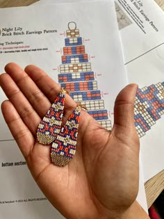 a person holding some kind of earrings in their hand on top of a piece of paper