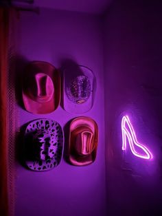 a purple light is shining on the wall and there are hats hanging up against it