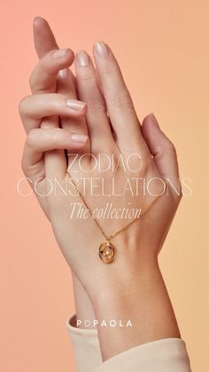 a woman's hand holding a gold necklace with the words zodiac constellations on it