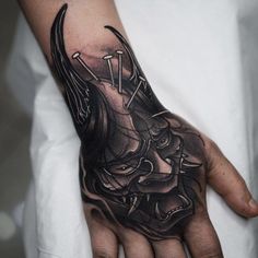 a person's hand with a black and grey tattoo design on the left palm