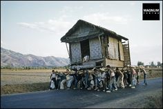 a group of people standing in front of a house on the side of a road