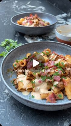 two bowls filled with pasta and meat on top of a stone table next to another bowl full of food