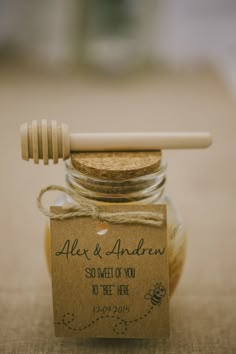 a jar filled with honey sitting on top of a table next to a wooden spoon