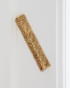 a close up of a door handle on the side of a white door with a gold weave pattern