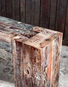 an old wooden bench sitting in front of a wood wall with peeling paint on it